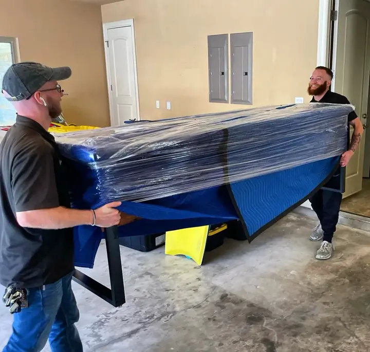 inNout Movers crew carrying a wrapped couch from a home